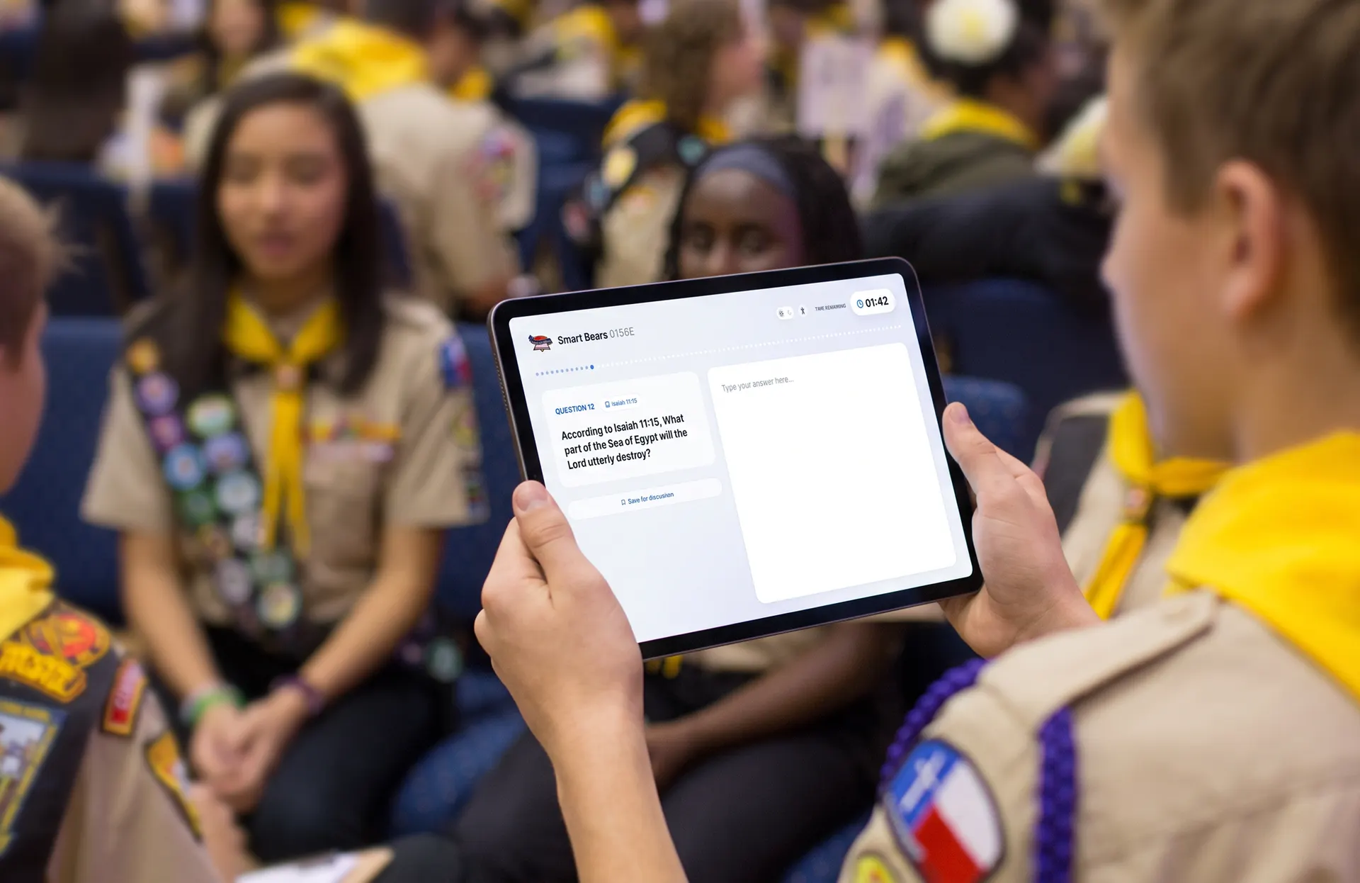 Design concept: a Pathfinder holding a tablet with a PBE question and a timer, other Pathfinders around them